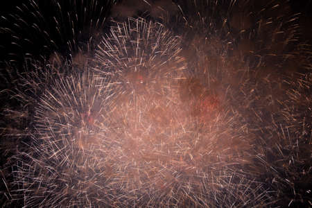 Golden and red sparks of fireworks and salutes in the sky and smoke from the charges