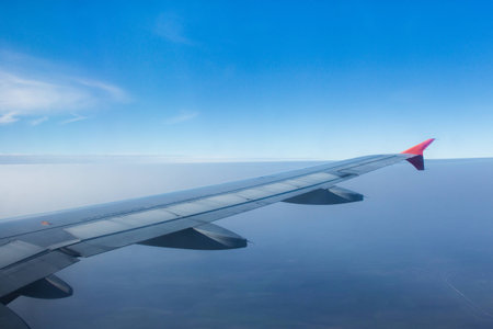 airplane wing in the air trough the window with terestrial view and blue sky