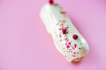 French dessert eclairs or profiteroles with rose-flavored white chocolate glaze, on a pink...