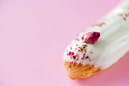 French dessert eclairs or profiteroles with rose-flavored white chocolate glaze, on a pink...