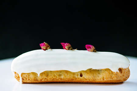 French dessert eclairs or profiteroles with rose-flavored white chocolate glaze, on a white...