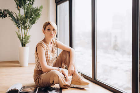 Stylish blonde woman in nude clothes reads a fashion magazine. Soft selective focus, artistic noise.の写真素材