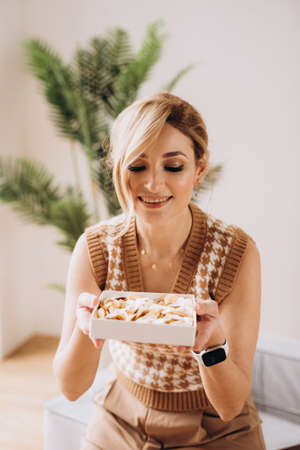 Beautiful blonde woman with a gift box in her hands with push-pop confetti. Gift for birthday, womens day, mothers day. Soft selective focus, defocus, art noise.の写真素材