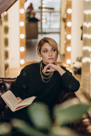 Beautiful blonde woman reads an interesting book in a cozy atmosphere at home. Soft selective focus,...
