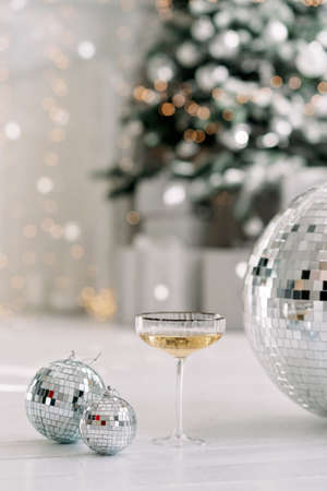 Happy New Year 2021. Christmas and New Year holidays minimal background, winter season. A glass of champagne against a background of bokeh lights. Soft selective focus.の写真素材