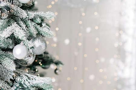 Christmas minimal background, a Christmas tree decorated with balls on a background of blurry bokeh lights. Baner, holiday card, mockup. New Year 2021. Soft selective focus, copy space.の写真素材