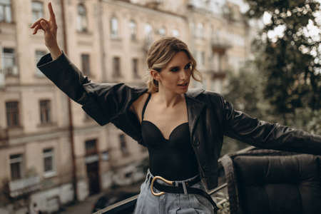 Stylish fashionable blonde woman with smoky eye make-up, in jeans, lingerie and black leather jacket...