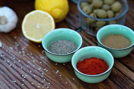 Oriental spices cumin, ground zira and red pepper paprika in bowls on a wooden oak table. Soft...