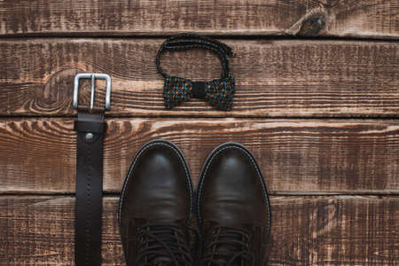 father's day with men's accessories belt and bow tie and leather shoes on a wooden background. Copy...