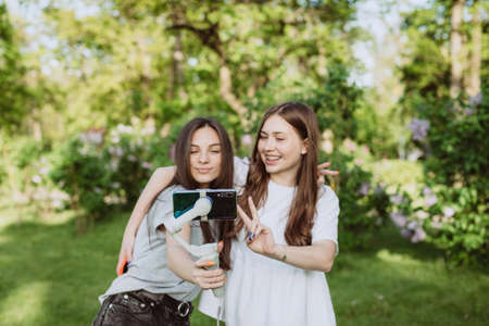 Smiling pretty young female influencer bloggers are filming or recording video with their mobile...