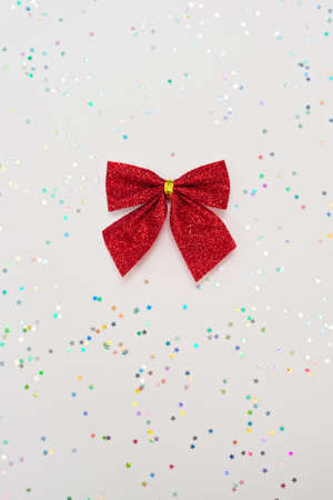 Christmas minimal composition. Red bow isolated on white background with glitter. New Year concept. Copy space.の写真素材