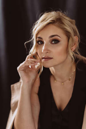 Fashionable close-up portrait of a beautiful stylish blonde woman with smoky eye makeup on a black background. Soft selective focus.の写真素材