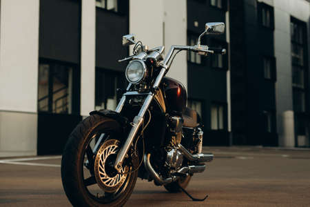 A motorcycle in a parking lot in the warm light of a sunset. Stylish custom chopper motobike with chrome details. Freedom, motorcycle travel. Soft selective focus.の写真素材