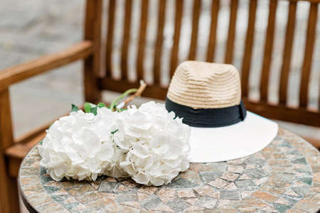 Lonely hat and white hydrangea flowers on a stone table. Romantic spring and summer background. Soft...