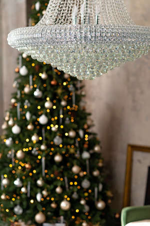 New year background. Christmas loft room interior. Lighting, large crystal chandelier, candles and indoor hot lighting, garlands. Christmas tree. Soft selective focus.の写真素材