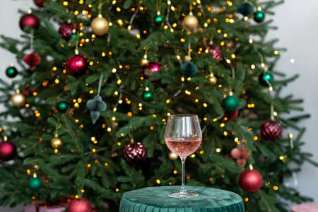 Glass of champagne rose against the background of bokeh lights of the Christmas tree. Winter holiday. New year background. Soft selective focus.の写真素材