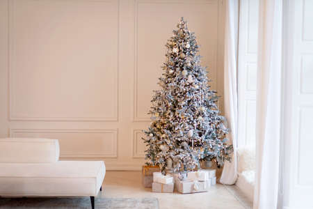 New Year tree is decorated with decorative balls and bokeh lights, with Christmas gift boxes near...