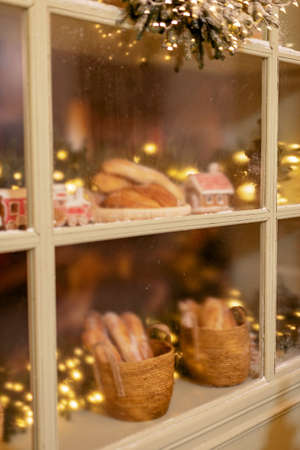 The snow-covered house is decorated for the new year. Vintage winter courtyard, decorated with Christmas trees, lanterns and a shop window with fresh baked goods. Soft selective focus.の写真素材