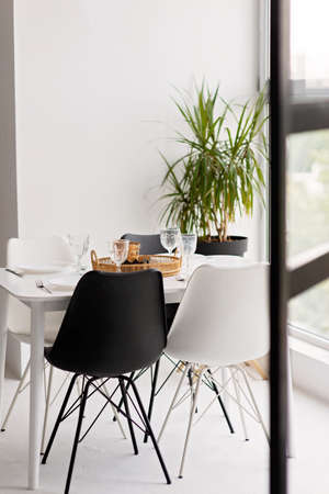 Modern interior of cozy kitchen, dining room, white furniture, chairs, bowls. Conceptual decor...