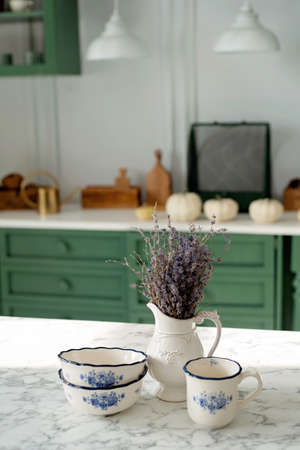 A bouquet of lavender and a set of white dishes: a porcelain milk jug, a coffee cup and bowls on a...