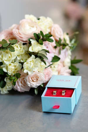 A pair of beautiful wedding rings and a delicate bridal bouquet of roses. Wedding ceremony. Soft...
