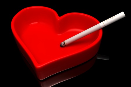 Red ashtray with a cigaret on a black background  の写真素材
