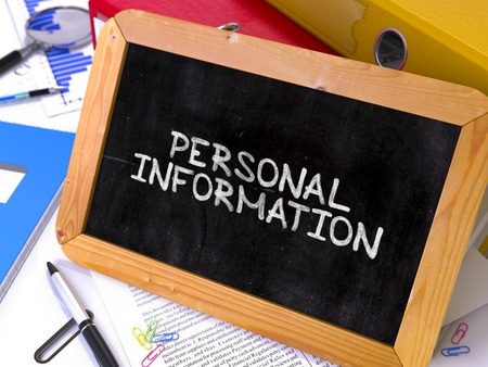 Personal Information Handwritten on Chalkboard. Composition with Small Chalkboard on Background of Working Table with Ring Binders, Office Supplies, Reports. Blurred Background. Toned Image.の写真素材