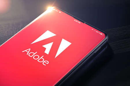 KYIV, UKRAINE-JANUARY, 2020: Adobe Systems Logo on Smartphone Screen. Adobe is a Multinational Software Company that Produces and Sells Multimedia and Creativity Software. 3D Render.のeditorial素材