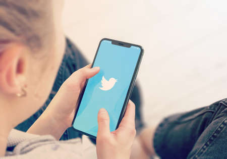 KYIV, UKRAINE-JANUARY, 2020: Twitter on Smart Phone Screen. Young Girl Pointing or Texting Cellphone During a Pandemic Self-Isolation and Coronavirus Prevention.のeditorial素材