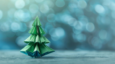 A green origami Christmas tree standing on a tableの素材