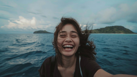 An exuberant woman with a joyful smile feeling the sea breeze on a boat trip.の素材