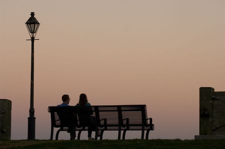 Couple sitting on the bench watching sunset by Mississippi river in New Orleansの写真素材