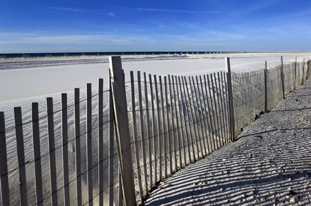 Empty white sand beach with fence in Alabama's Gulf of Mexico coastの写真素材