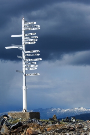 Direction pole with world cities signs on the top of Alaska's mountainの写真素材
