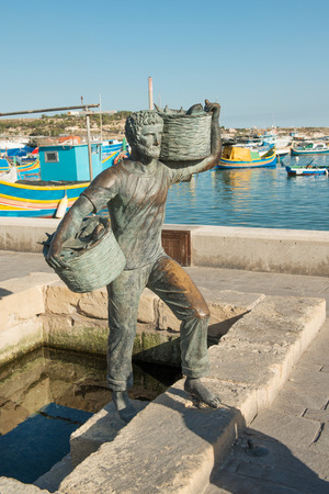 Fisherman statue on embankment of famous Marsaxlokk village Maltaの写真素材