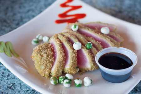 Seared fresh Ahi tuna slices with wasabi peas and sauceの写真素材