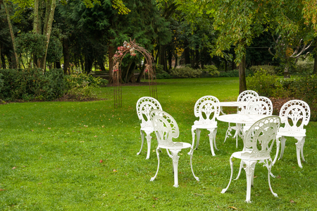 White garden furniture and ceremony arch on manicured green lawnの写真素材