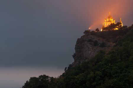 Popular scenic Church of Christ Resurrection on the cliff above Black Sea coastline near Foros, Crimea, illuminated at duskの写真素材