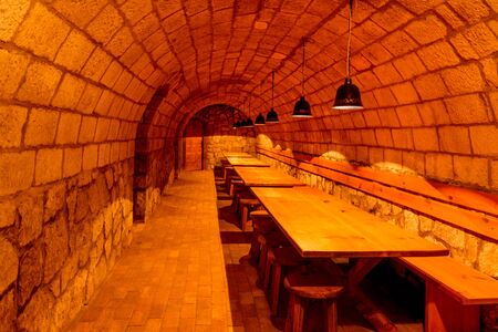 Long wooden tables and benches in cozy underground pub in wine cellarのeditorial素材
