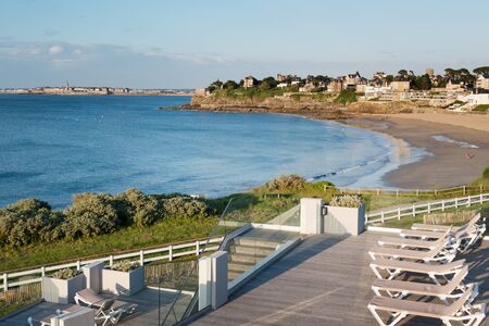 Sunbeds and sandy beach in Dinard, famous holiday destination on Breton coastline, with Saint-Malo in the distance, Brittany, Franceの写真素材