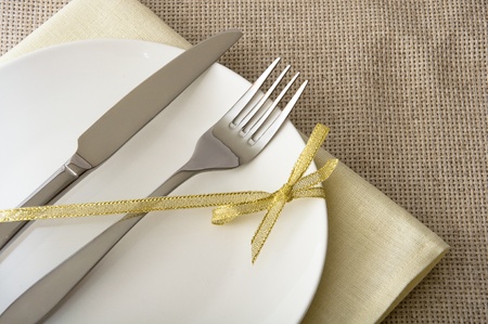 fork and knife on a white plate with a gold ribbon