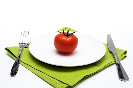 single red tomato on whitï¿½ plate with knife and forkの写真素材