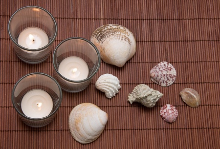 three tea candles with seashells on a dark backgroundの写真素材