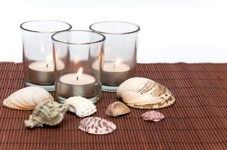 three tea candles with seashells on a dark backgroundの写真素材