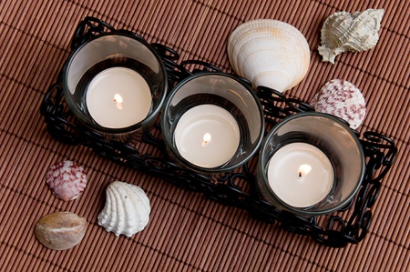 three tea candles with seashells on a dark backgroundの写真素材