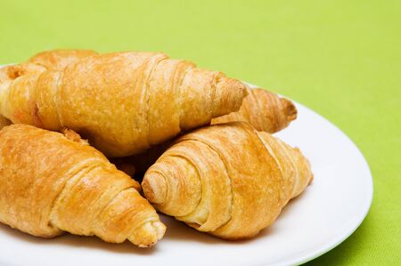 five croissants in a white plate on a green backgroundの写真素材