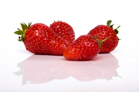Four strawberries isolated on white background with reflectionの写真素材