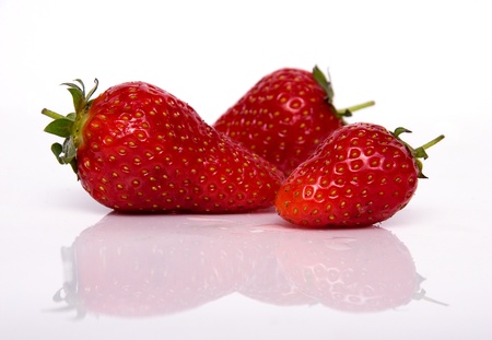 Three strawberries isolated on white background with reflectionの写真素材