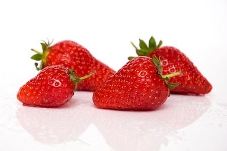 Four strawberries isolated on white background with reflectionの写真素材