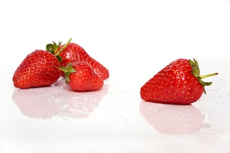 Four strawberries isolated on white background with reflectionの写真素材